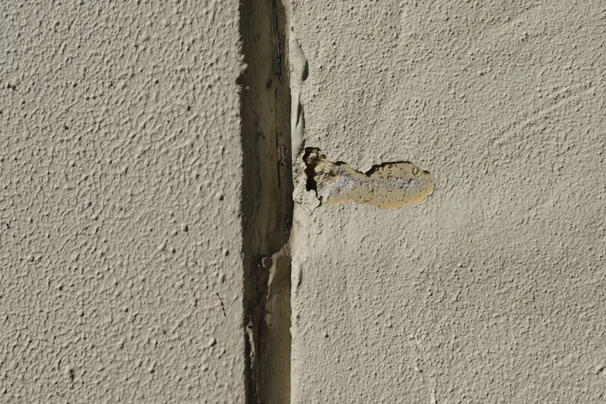 Crack and damage along a rendered exterior wall surface.